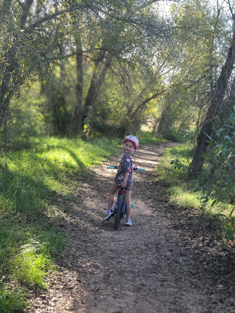 Bellamy riding her bike along a wooded trail.