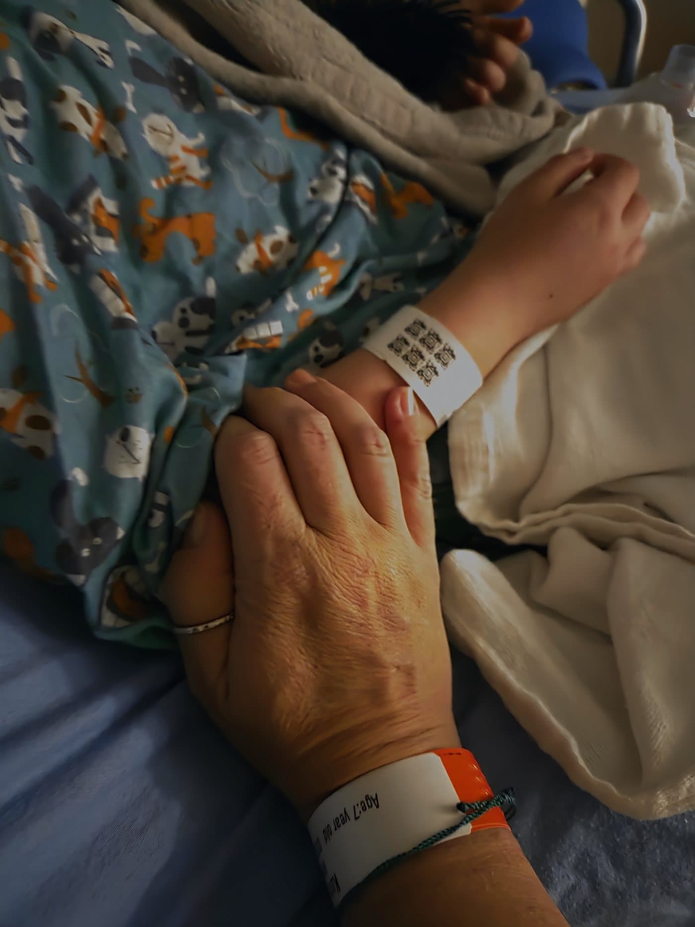 A hand resting gently on Bellamy arm, beside her hospital wristband.