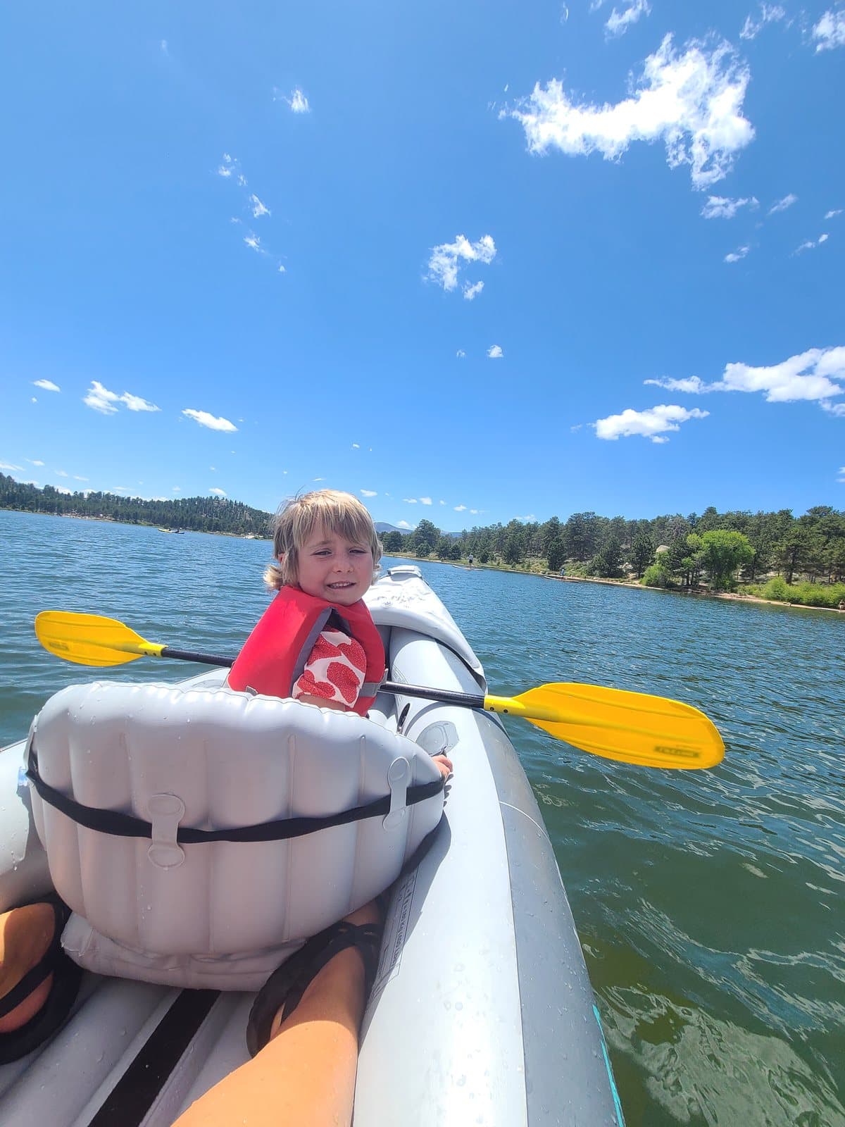 Bellamy sitting in a kayak on a bright blue lake.