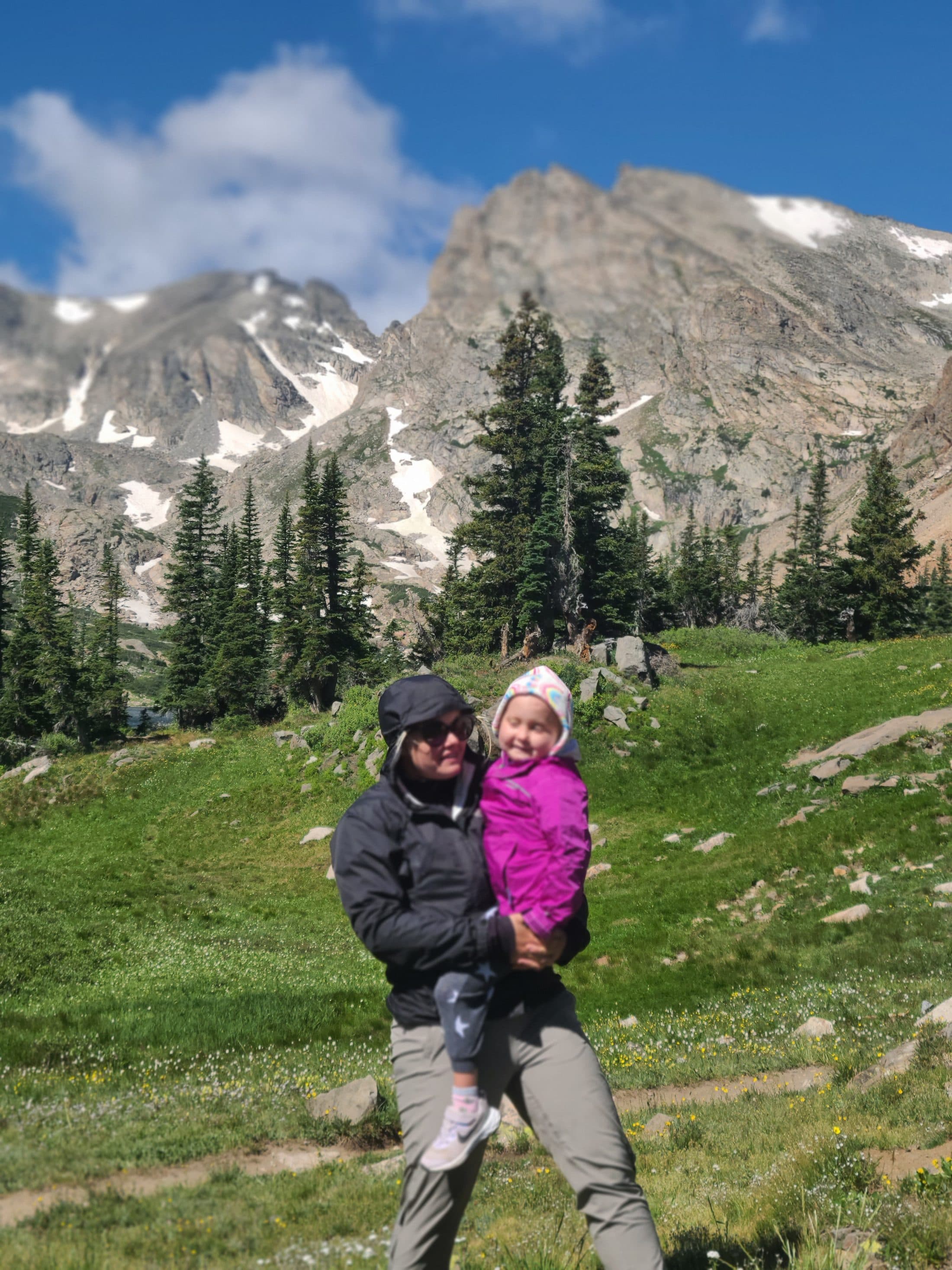 A mother holding her daughter at the shore of Lake Isabelle.