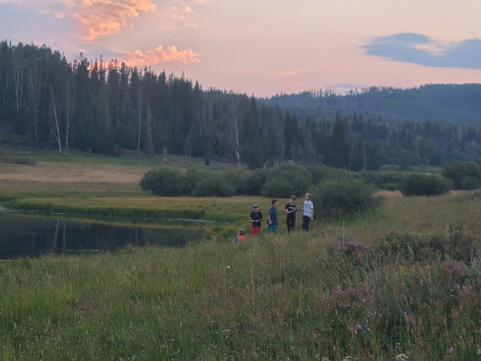 Siblings fishing at a mountain lake.