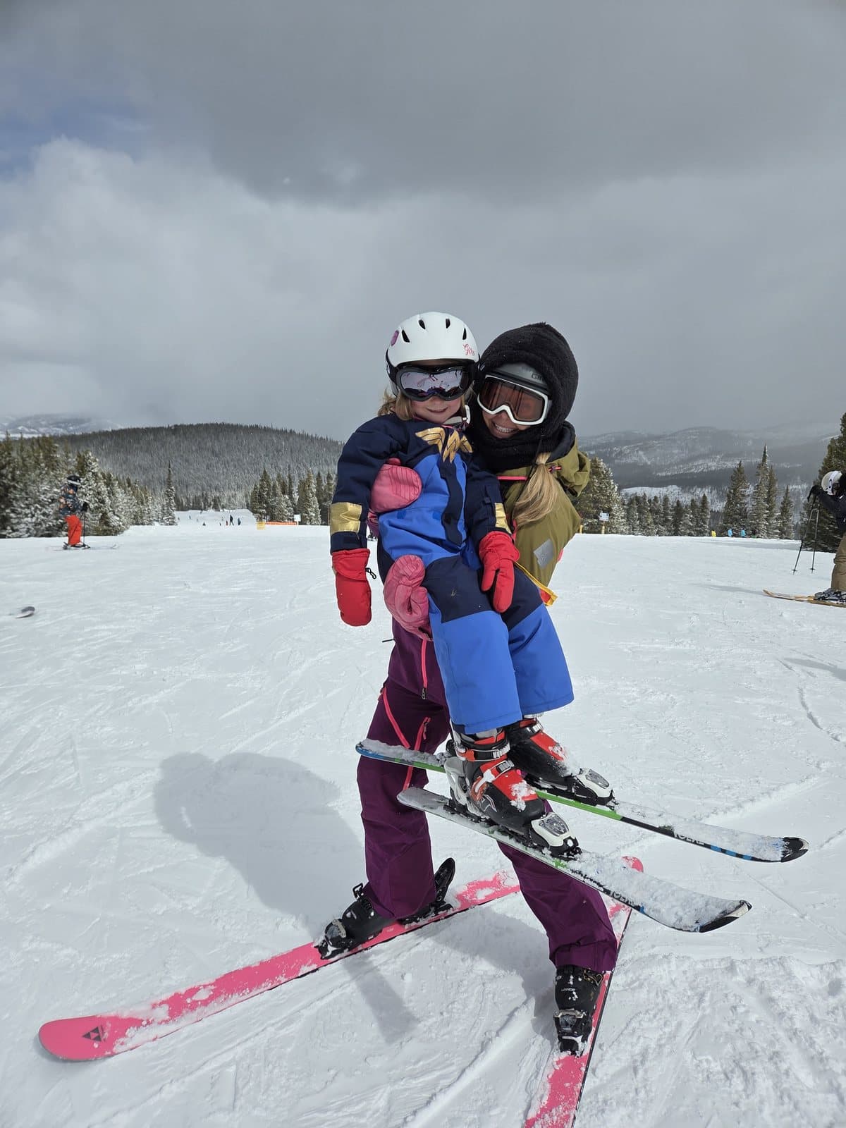 Sarah and Bellamy on skis together, helmets on.