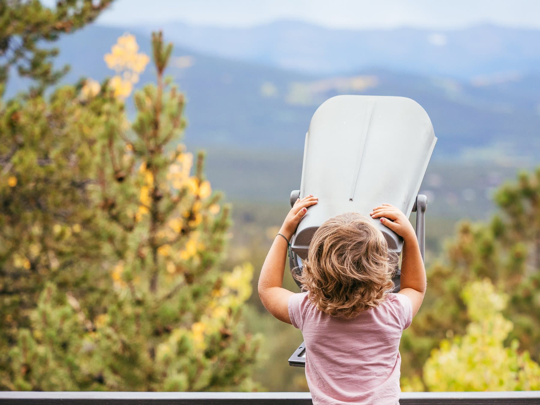 A child at a mountain viewfinder, looking out over the Colorado hills.